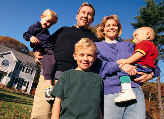 Family of five standing in front of their home