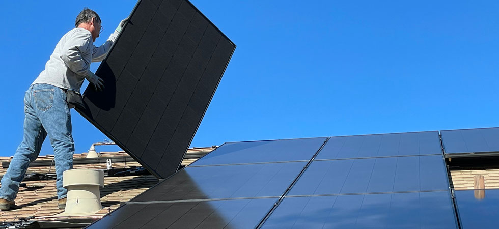 Man on house roof installing solar panels